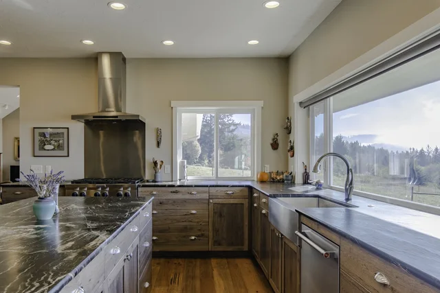Warm wood cabinetry framing a bright kitchen and landscape view