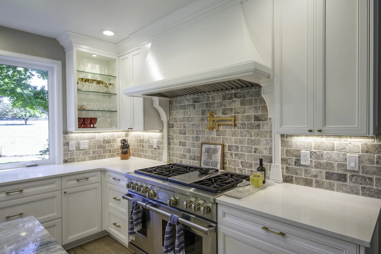 White framed kitchen cabinetry and a custom hood surround