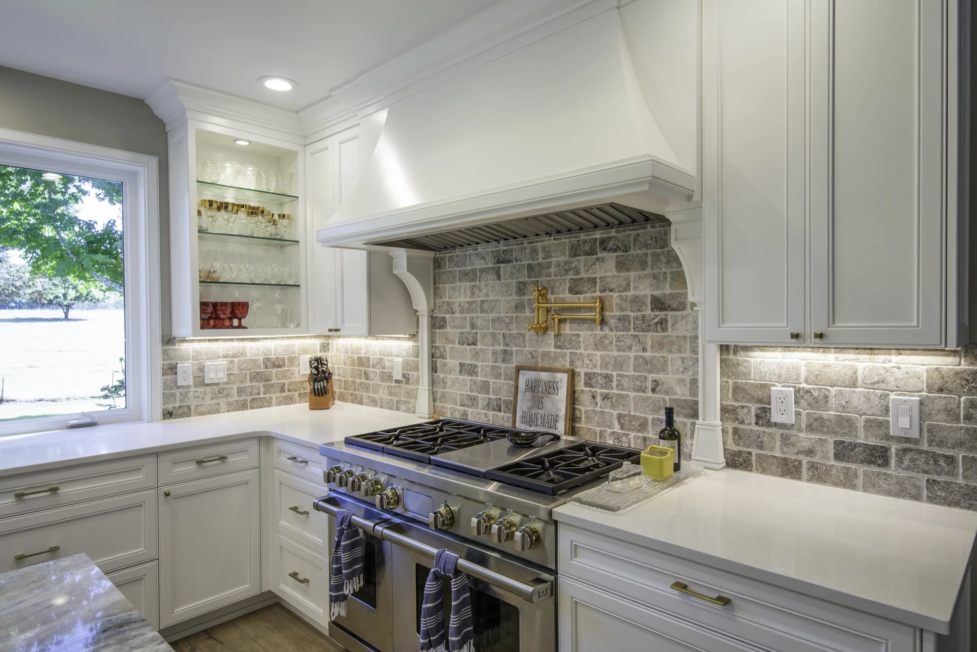 White framed cabinets and custom hood surround at a range