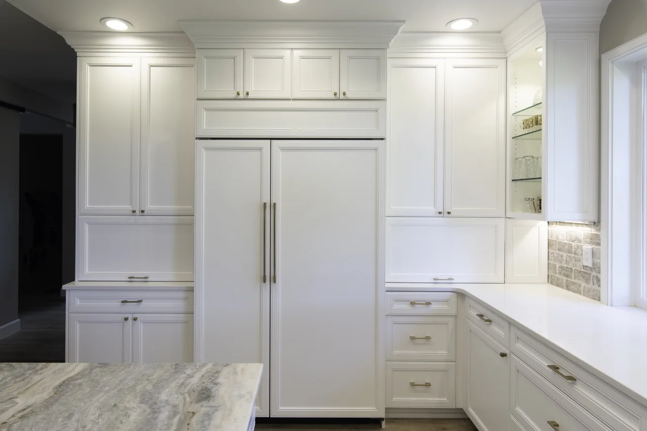 Full wall of white kitchen storage around a refrigerator