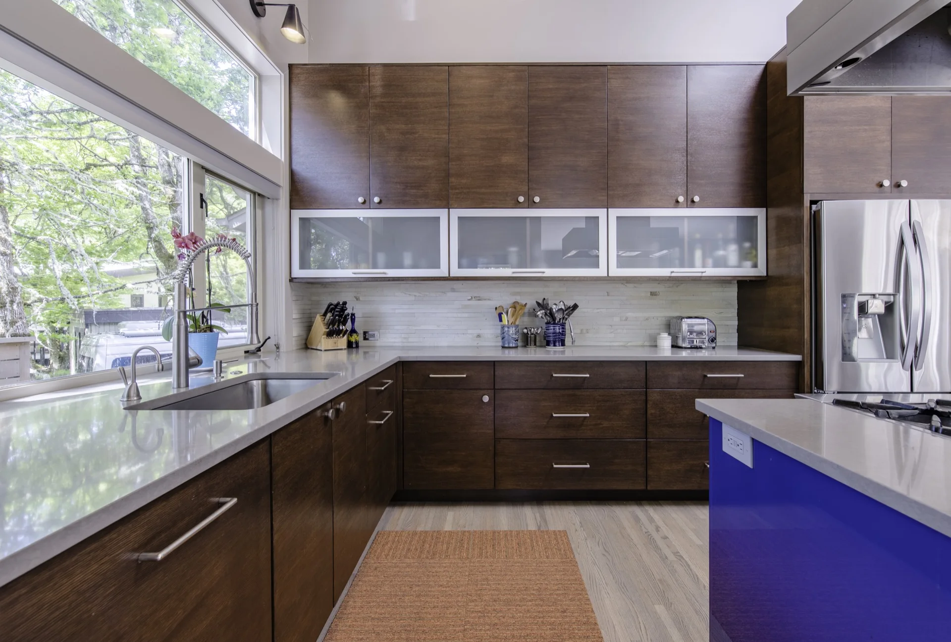 Modern walnut kitchen with glass-front upper cabinets and broad drawers