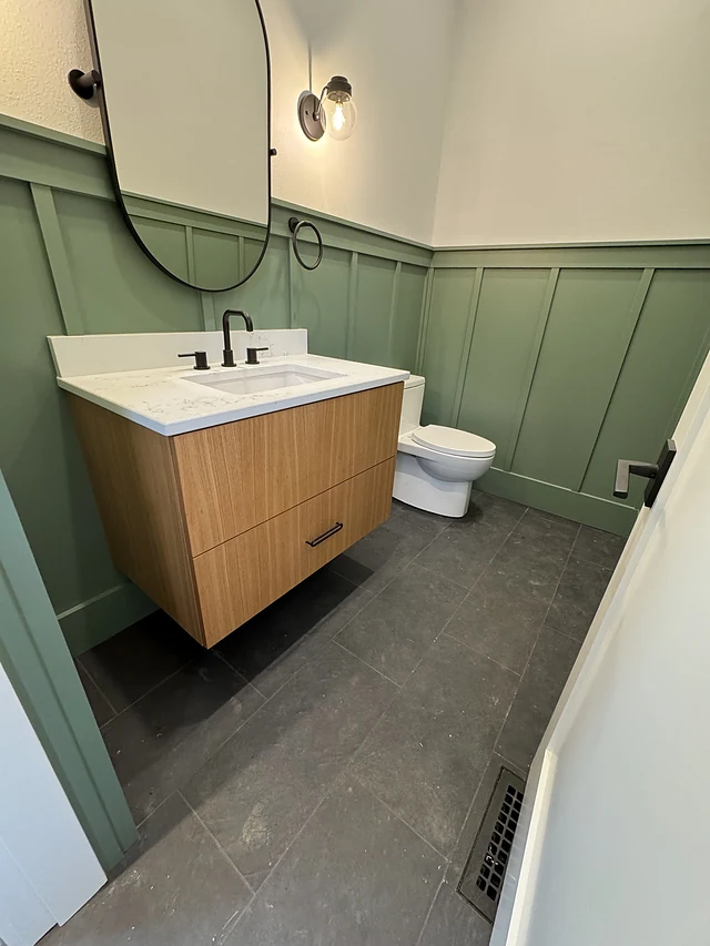 Floating wood vanity against green paneling